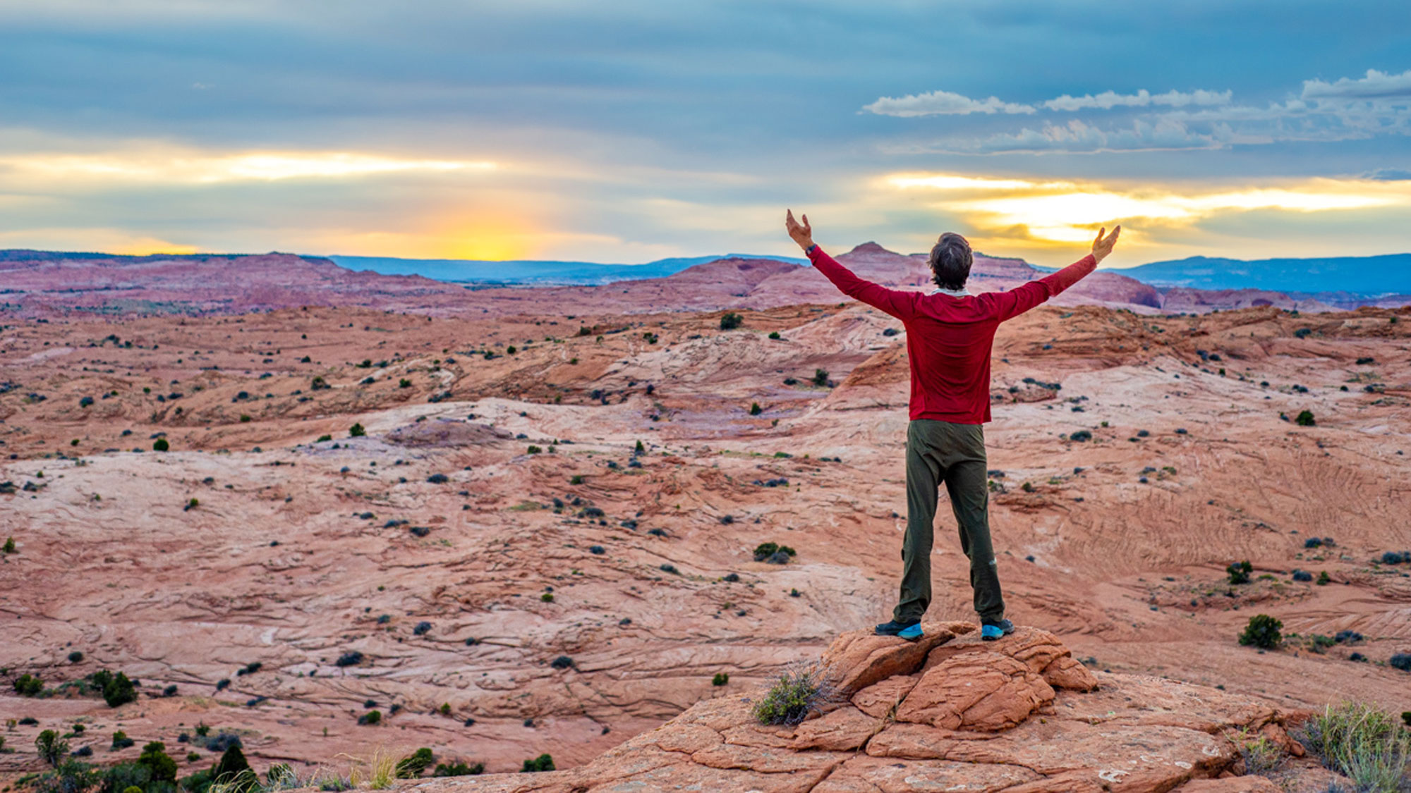 Man with his hands raised with sunset in desert